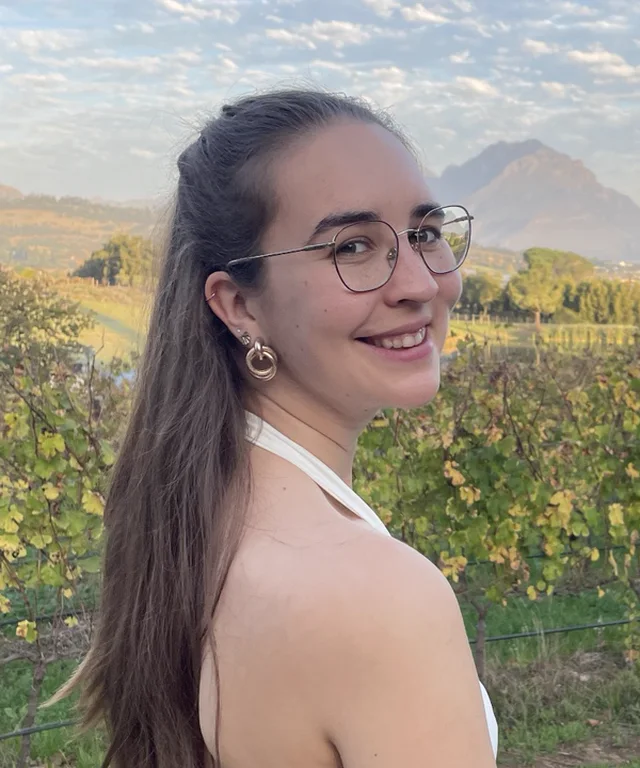 Pauline vor einem Weinberg und einer Berglandschaft